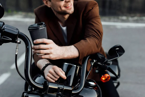 Vista cortada do homem segurando xícara de papel de café enquanto sentado na motocicleta — Fotografia de Stock