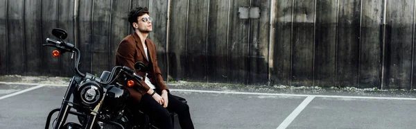 Панорамний знімок людини в коричневій куртці відпочиває на мотоциклі — стокове фото