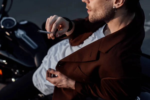 Cropped view of man smoking cigarette while sitting on motorcycle — Stock Photo