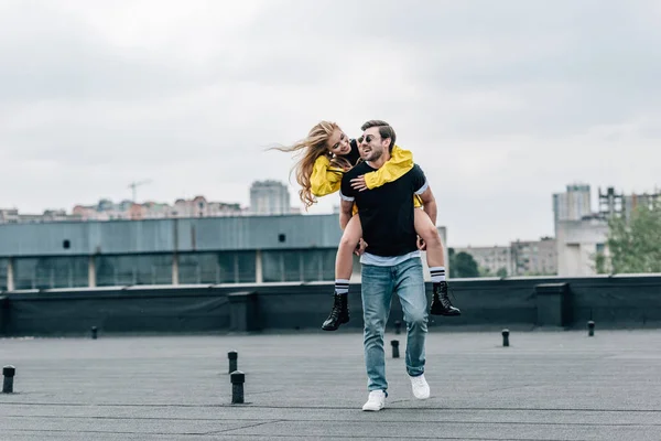 Привлекательная женщина и красивый мужчина улыбается и играет на крыше — стоковое фото