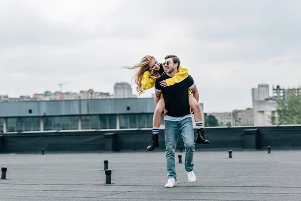 Atractiva mujer y hombre guapo sonriendo y jugando en el techo - foto de stock