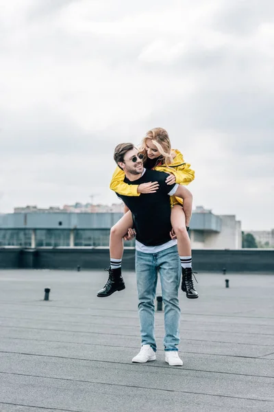 Attrayant femme et bel homme souriant et jouant sur le toit — Photo de stock