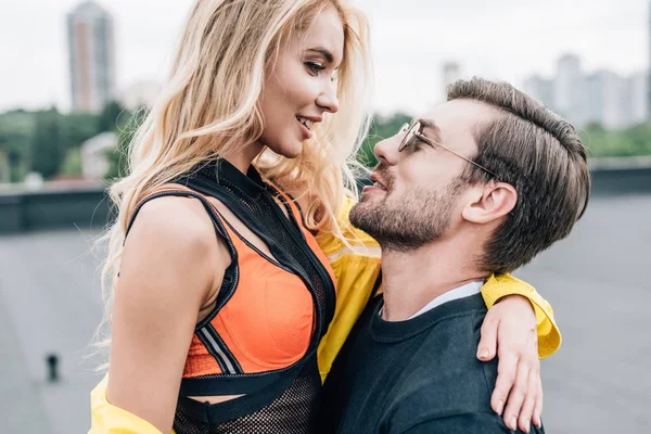 Mujer atractiva y rubia abrazándose con hombre guapo en gafas - foto de stock