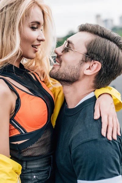 Handsome man in glasses holding attractive woman on roof — Stock Photo