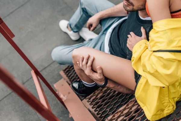 Cropped view of woman and man hugging and sitting on stairs — Stock Photo