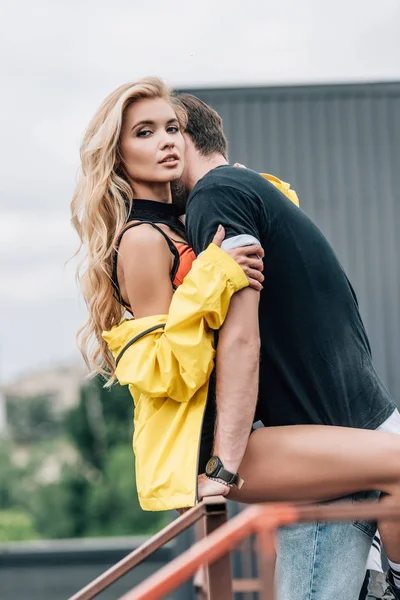 Femme blonde et homme en t-shirt étreignant et regardant la caméra — Photo de stock