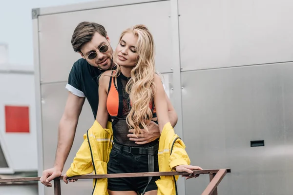 Blonde woman and handsome man in glasses hugging on roof — Stock Photo