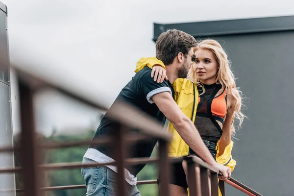 Femme blonde et bel homme étreignant et se regardant sur le toit — Photo de stock