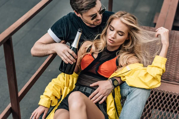 Handsome man in glasses holding bottle and hugging with attractive woman — Stock Photo