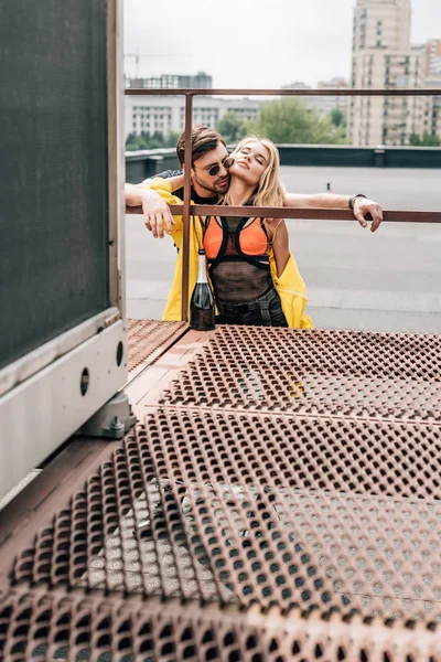 Blonde woman and handsome man in glasses hugging on roof — Stock Photo