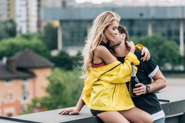 Mann hält Flasche, küsst attraktive Frau und umarmt sie — Stockfoto