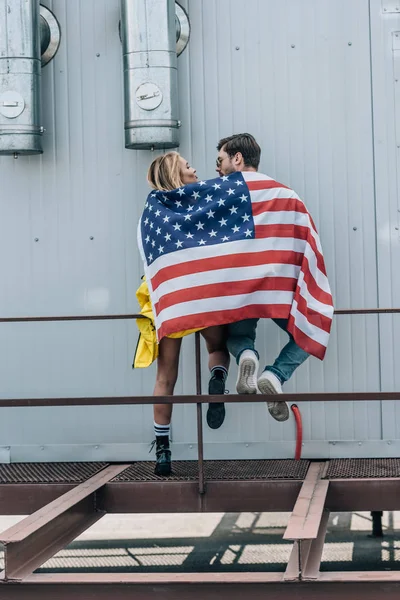 Vista posteriore di donna e uomo con bandiera americana sul tetto — Foto stock