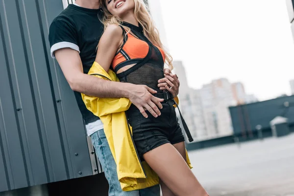 Cropped view of woman and man in jeans and t-shirt hugging on roof — Stock Photo