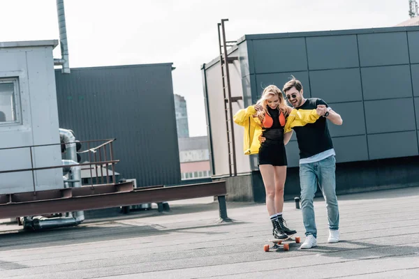 Attractive woman skateboarding and man in glasses hugging her — Stock Photo