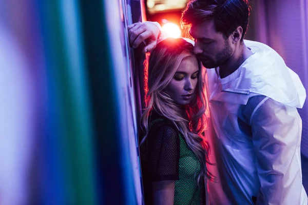 Attractive and blonde woman standing with handsome man near wall — Stock Photo