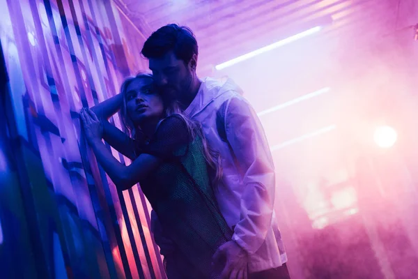 Attractive and blonde woman hugging with handsome man near wall — Stock Photo