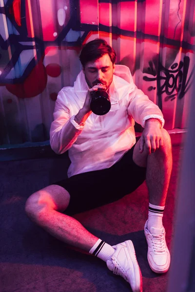 Handsome man sitting on floor and drinking champagne in night club — Stock Photo