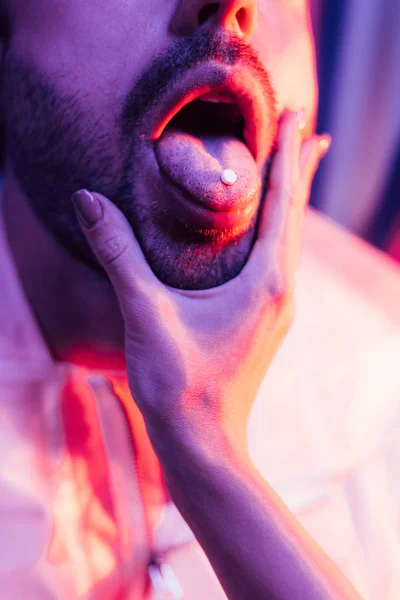 Vista recortada del hombre con LSD en la lengua y la mujer tocando su cara - foto de stock