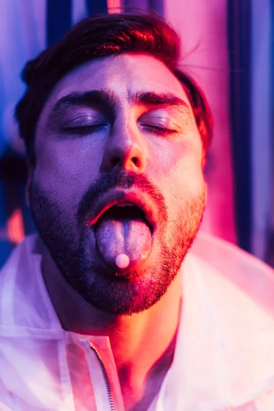 Hombre guapo con los ojos cerrados y LSD en la lengua - foto de stock