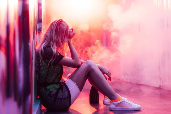 Side view of blonde and sad woman sitting on floor — Stock Photo