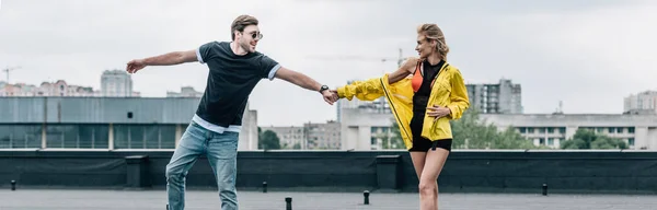 Plano panorámico de mujer atractiva y rubia y hombre guapo cogido de la mano - foto de stock