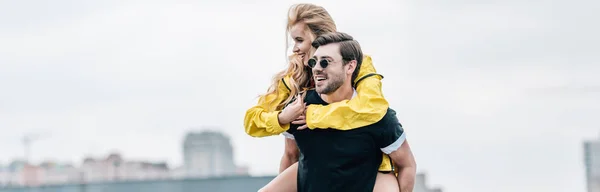Panoramic shot of attractive and blonde woman and handsome man hugging on roof — Stock Photo