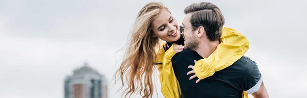 Plano panorámico de mujer atractiva y rubia y hombre guapo abrazando y sonriendo en el techo - foto de stock