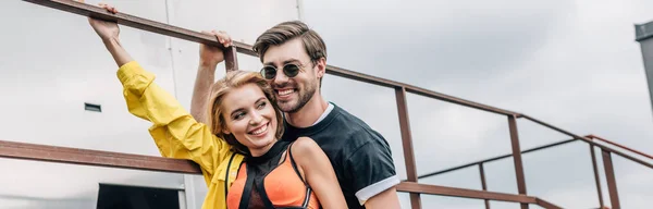 Panoramic shot of attractive and blonde woman and handsome man hugging on roof — Stock Photo