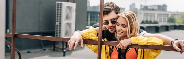 Panoramic shot of attractive and blonde woman and handsome man hugging on roof — Stock Photo