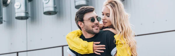 Panoramic shot of attractive and blonde woman and handsome man hugging on roof — Stock Photo