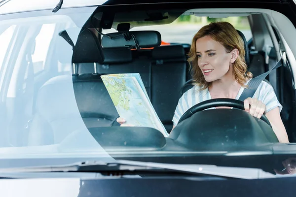 Selective focus of woman looking at map and driving car — Stock Photo