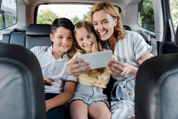 Foyer sélectif de la famille joyeuse prendre selfie sur smartphone en voiture — Photo de stock