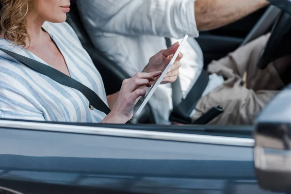 Cropped view of woman using digital tablet near driver in car — Stock Photo