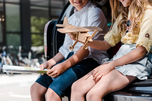 Cropped view of happy brother near sister holding toy biplane near car — Stock Photo