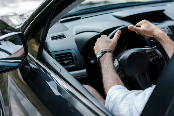 Cropped view of man holding steering wheel while driving automobile — Stock Photo