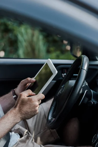 Cropped view of man holding digital tablet and sitting in car — Stock Photo