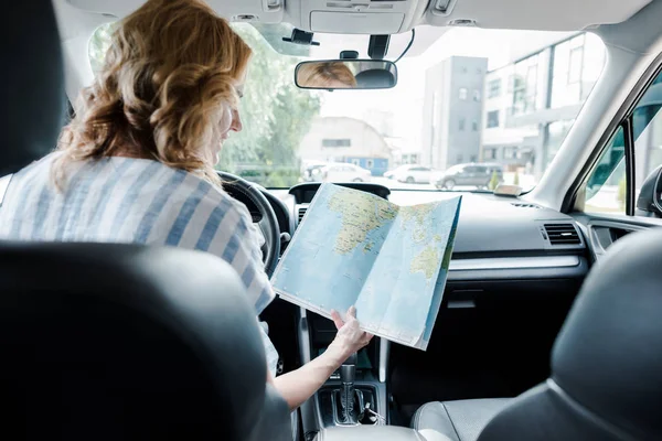 Selective focus of happy woman holding map while sitting in car — Stock Photo