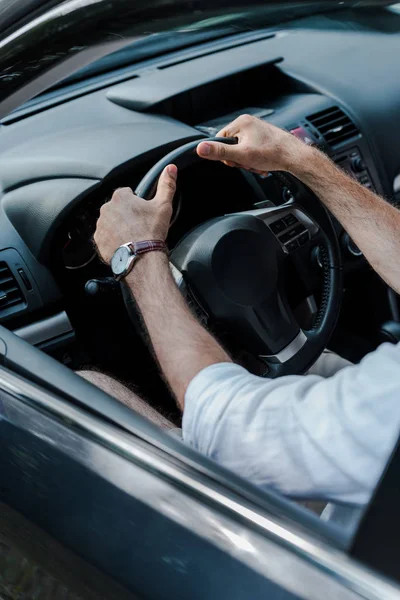 Cropped view of man holding steering wheel and driving automobile — Stock Photo