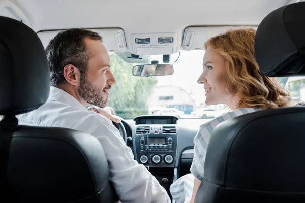 Foco seletivo do homem feliz olhando para a mulher alegre no carro — Fotografia de Stock