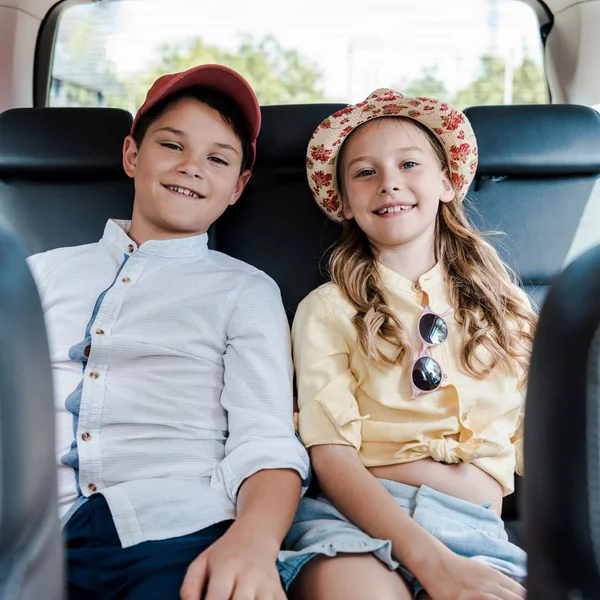 Selective focus of positive sister and brother sitting in car — Stock Photo