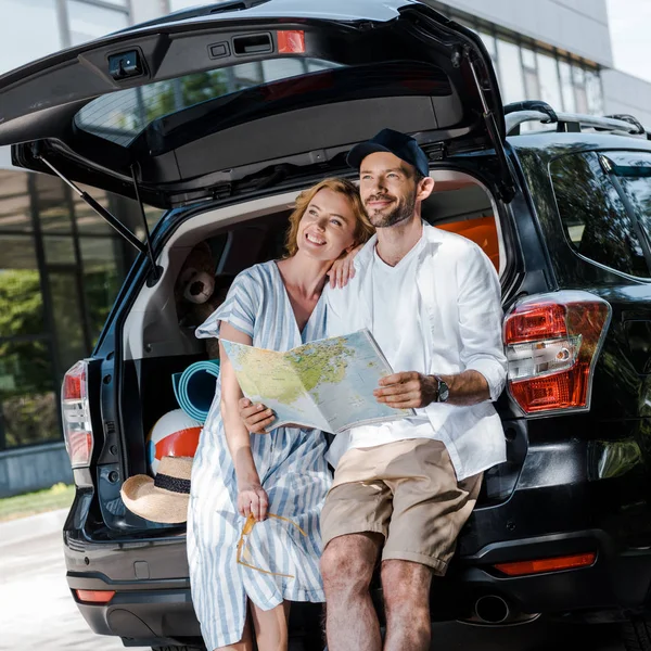 Homem alegre segurando mapa perto de carro e mulher loira feliz — Fotografia de Stock