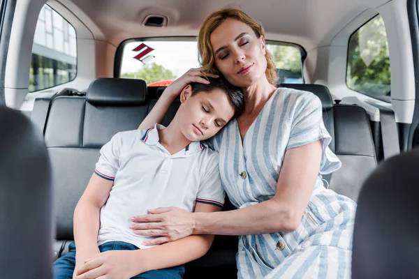 Selective focus of mother and son with closed eyes in car — Stock Photo