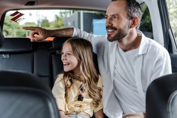 Selektive Fokussierung des glücklichen Vaters, der mit dem Finger in der Nähe von Molkereien im Auto zeigt — Stockfoto