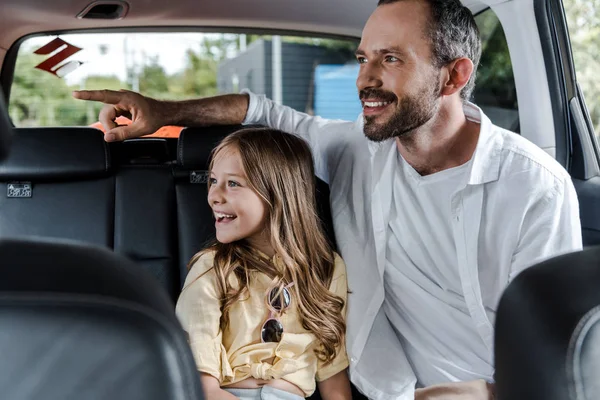 Messa a fuoco selettiva del padre felice che punta con il dito vicino a Daighter in auto — Foto stock