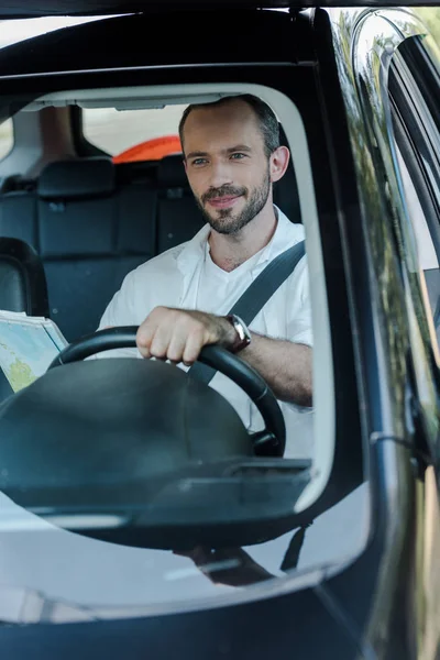 Вибірковий фокус красивого чоловіка, який керує автомобілем і тримає карту — стокове фото