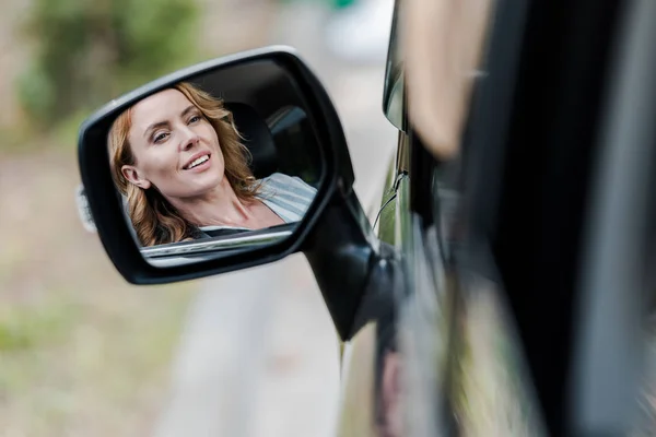 Gai blonde et attrayant femme souriant dans la fenêtre de la voiture — Photo de stock