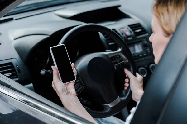 Обрезанный вид женщины, держащей смартфон с пустым экраном в машине — стоковое фото