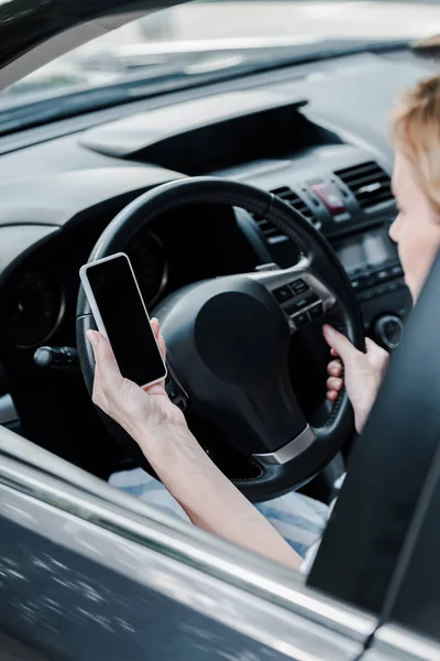 Vue recadrée de la femme tenant smartphone avec écran blanc dans l'automobile — Photo de stock