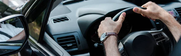 Panoramic shot of man holding steering wheel and driving automobile — Stock Photo