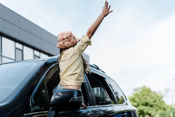 Low angle view of kid with outstretched hand in car window — Stock Photo